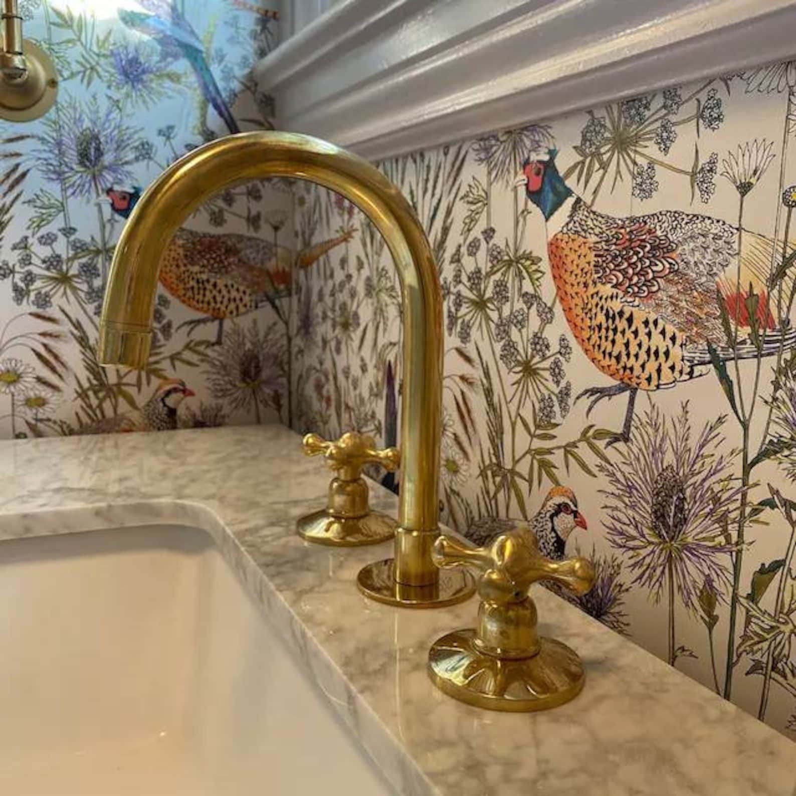 Unlacquered brass bathroom faucet with round handles