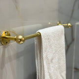 Gold towel rack with a white towel on a marble wall