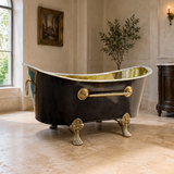 A freestanding clawfoot bathtub with a glossy black exterior and gold brass interior.