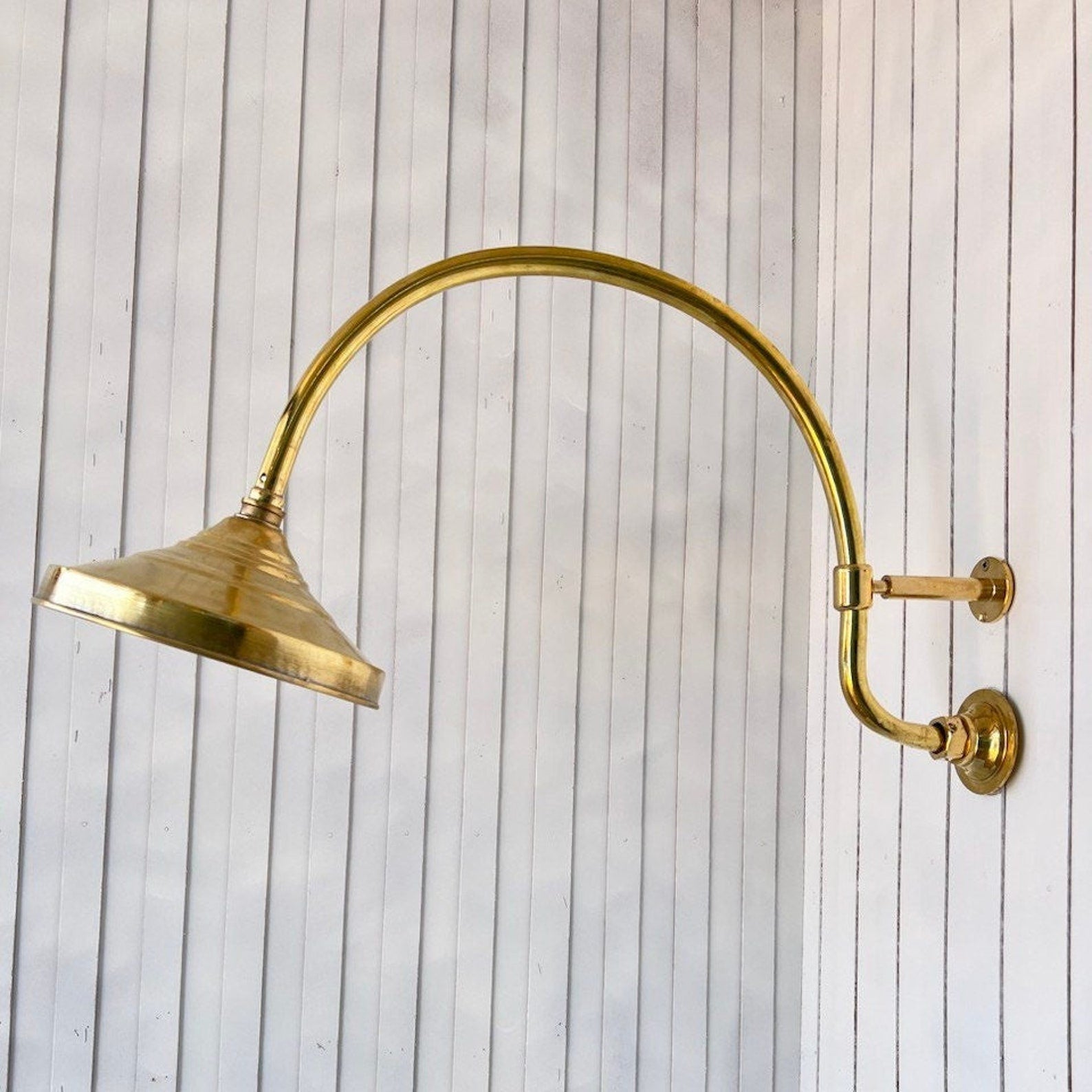 unlacquered brass shower head with curved extension